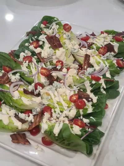 Classic wedge salad with blue cheese crumbles, crispy bacon, and cherry tomatoes by Chef Mollie